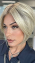 Model is wearing AYUMI by NORIKO in color Light Ash Blond R | Cream Ash Blonde with ash brown and white-grey roots that blend into a variety of ash blonde tones, including ash pearl blonde, creamy ivory, and pale cream
