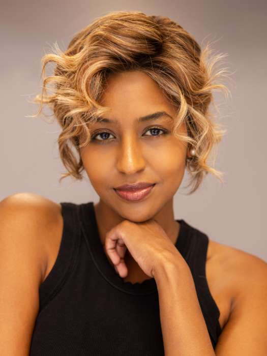 Model is wearing Twisted Pixie by TressAllure in shade EL17/23/R8 | Pale Auburn Beige Blonde Blend, Rooted Medium Brown, Highlighted Light Blonde with face framing highlights