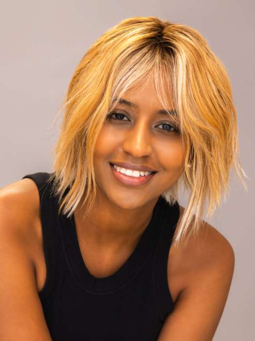 Model is wearing ROSANNA by RENE OF PARIS in shade PEACHES-AND-CREAM | A vibrant peach blonde with creamy undertones and bright, face-framing cream highlights. Rich chocolate root adds depth.