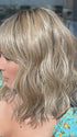 Model is wearing FRANKIE by ESTETICA in color RH12/26RT4 | Light Brown with Fine Golden Blonde Highlights And Dark Roots