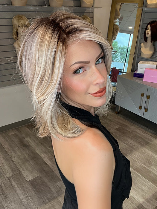 Madeline wearing PARK AVE by BELLE TRESS in color MILKSHAKE BLONDE R | A mixture of Light Sandy Brown, Highlighted with Light Ash Blonde with a Hint of Light Platinum Blonde with a Medium Root Color