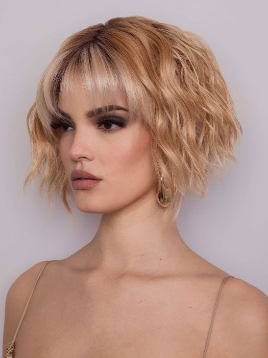 Model is wearing ROSANNA by RENE OF PARIS in color PEACHES AND CREAM | A vibrant peach blonde with creamy undertones and bright, face-framing cream highlights. Rich chocolate root adds depth.